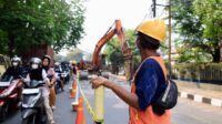 Petugas mengatur arus kendaraan di sekitar lokasi perbaikan Jalan Raya M. Toha, Kota Tangerang. Pengendara diimbau berhati-hati dan menyesuaikan rute perjalanan selama proyek berlangsung.